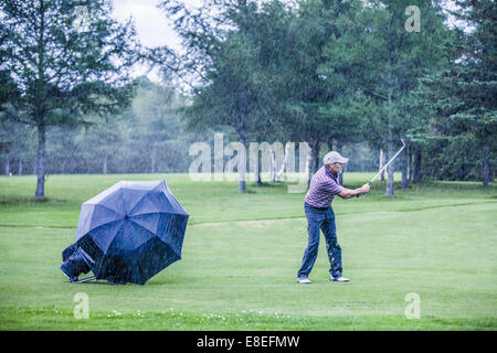 Giocatore di golf in un giorno di pioggia Swigning al Fairway (concetto di motivazione) Foto Stock