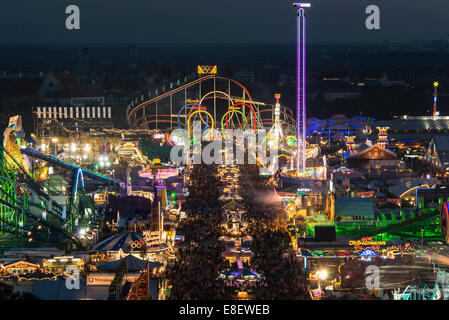 Corse su la fiera di strada con Olympia looping, Fünferlooping roller coaster di notte, Oktoberfest Theresienwiese, Monaco di Baviera Foto Stock