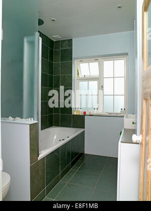 Nero parete piastrelle e box doccia in vetro pannello sopra la vasca da bagno in stile anni trenta grigio e stanze da bagno di colore bianco Foto Stock