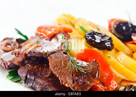 Stufati di carne di montone con patate e prugne nero su una piastra bianca Foto Stock