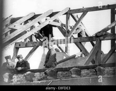 Costruzione di lavoratori di Berlino Est sono sotto stretta sorveglianza da parte dei membri del popolo della polizia quando essi abbattere case confinanti in Bernauer Street a Berlino, 9 marzo 1965. Gli inquilini della casa sono stati reinsediati in corso del regime obbligatorio di evacuazione. Dal 13 agosto 1961, il giorno della costruzione del muro di Berlino, fino alla caduta del muro di Berlino del 9 novembre 1989, la Repubblica federale di Germania e della Repubblica democratica tedesca sono stati separati dalla cortina di ferro tra Occidente e Oriente. Foto Stock