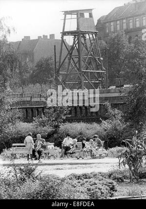 I cittadini di Berlino Ovest per godersi il sole in un parco nel quartiere Kreuzberg direttamente di fronte al muro di Berlino e una torre di vedetta dietro di esso, 11 settembre 1963. Dal 13 agosto 1961, il giorno della costruzione del muro di Berlino, fino alla caduta del muro di Berlino del 9 novembre 1989, la Repubblica federale di Germania e della Repubblica democratica tedesca sono stati separati dalla cortina di ferro tra Occidente e Oriente. Foto Stock