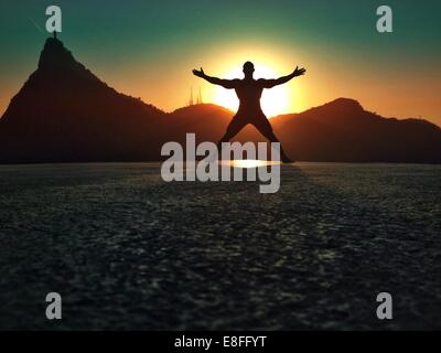 Silhouette di uomo messing about sulla spiaggia al tramonto, Rio de Janeiro, Brasile Foto Stock