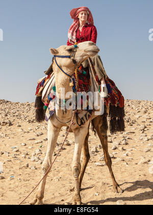 Donna seduta sul cammello nel deserto di Giza in Egitto Foto Stock