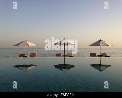 Ombrelloni e sdraio riflessioni in una piscina Foto Stock