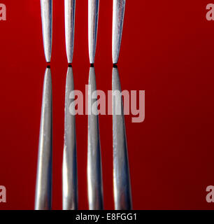 Close up dei rebbi della forcella rossa sulla superficie riflettente, studio shot Foto Stock