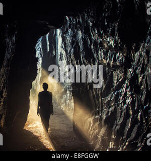 Silhouette di una donna che cammina in una grotta Foto Stock