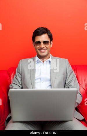 Ritratto di un uomo di affari usando un computer portatile, indossando occhiali da sole Foto Stock