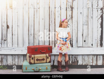 Ragazza in piedi da una pila di valigie all'aperto, California, Stati Uniti Foto Stock