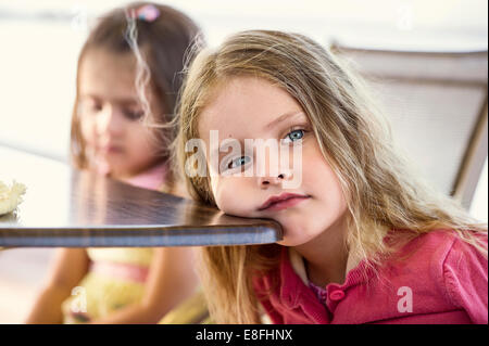 Ragazza in appoggio la sua testa su un tavolo Foto Stock