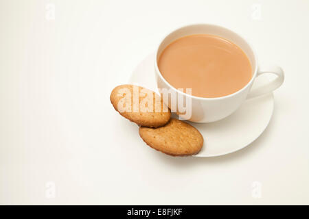 Primo piano di una tazza di tè con latte e due biscotti digestivi Foto Stock
