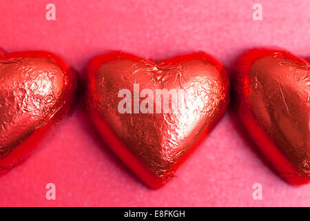 Primo piano di tre cioccolatini a forma di cuore in un involucro di alluminio Foto Stock