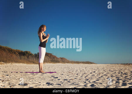 Donna fare yoga sulla spiaggia Foto Stock