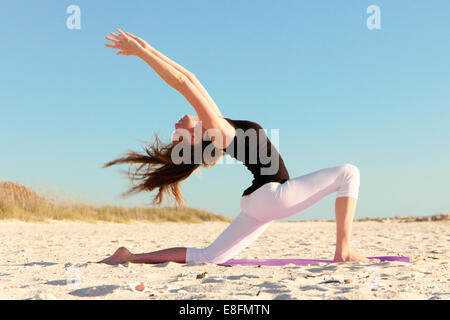 Donna fare yoga sulla spiaggia Foto Stock