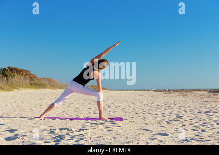 Vista posteriore della donna fare yoga sulla spiaggia Foto Stock