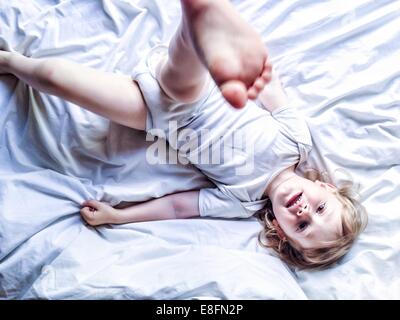 Ragazzo disteso sul letto di calci la sua gamba in aria Foto Stock