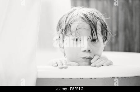 Ritratto di un ragazzo che guarda sul bordo di una vasca da bagno Foto Stock