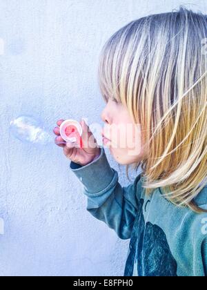 Ragazzo tenendo una bolla wand soffiando bolle di sapone Foto Stock