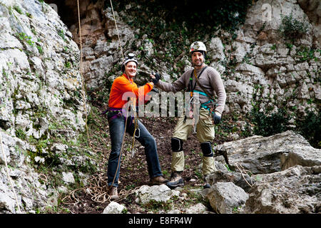 Italia, due uomini che indossano cavi di sicurezza in piedi nella parte anteriore della grotta Foto Stock