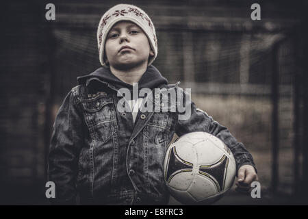 Ritratto di un ragazzo serio tenendo un calcio Foto Stock