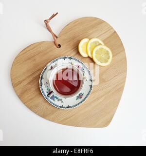 Il tè e le fette di limone su un tagliere Foto Stock