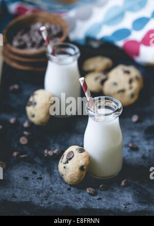 Biscotti al cioccolato e bottiglie di latte Foto Stock