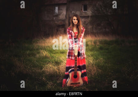 Ragazza sorridente in piedi in un prato con la sua chitarra, Polonia Foto Stock