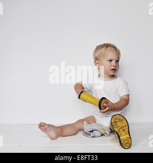 Ragazzo mettendo in stivali da pioggia Foto Stock