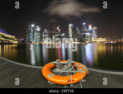 Skyline della città di notte con lifebelt sul dock, Marina Bay, Singapore Foto Stock