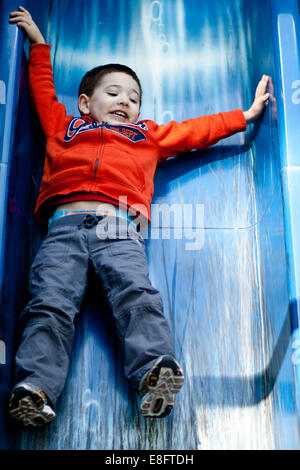 Ragazzo scivolare giù scorrere nel parco giochi Foto Stock