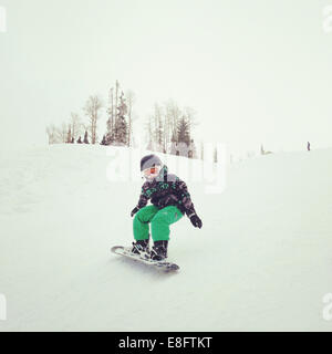 Ragazzo Snowboard giù per la collina Foto Stock