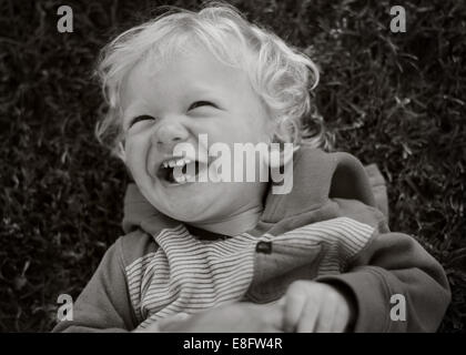 Bambino giacente su erba ridere Foto Stock