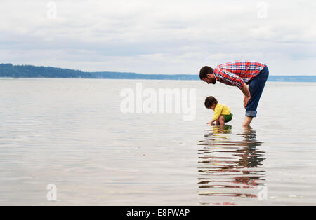 Padre e figlio in piedi in un lago che guarda verso il basso, Stati Uniti Foto Stock