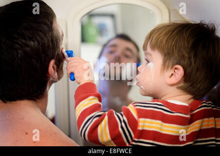 Ragazzo che aiuta il padre a radersi Foto Stock