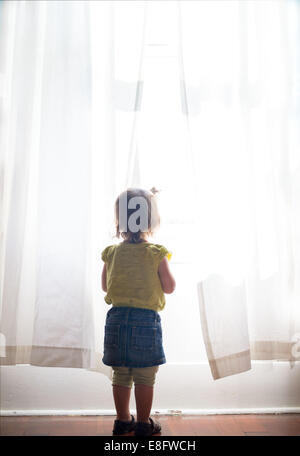 Ragazza guardando fuori della finestra Foto Stock