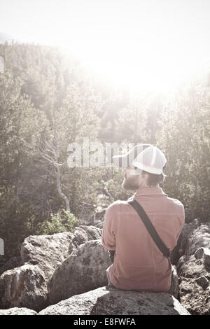 Stati Uniti d'America, Wyoming uomo seduto sulle rocce al di sopra degli alberi Foto Stock
