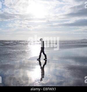 Uomo a camminare sulla spiaggia Foto Stock