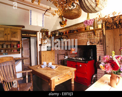 Le ceste sulla cremagliera in legno sopra il vecchio tavolo di pino in cucina di paese con red Aga Foto Stock