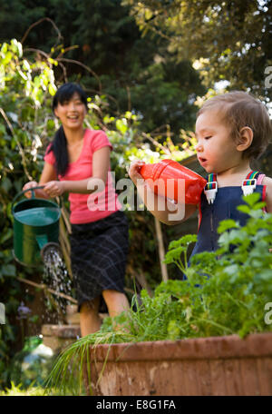 Un misto di etnia (East Asian / caucasica) toddler femmina nel piccolo giardino urbano a casa con la sua coreano East Asian madre, t Foto Stock