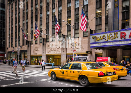 A New York Yellow Cab attende per i pedoni a croce al di fuori della Radio City Music Hall in Midtown Manhattan. Foto Stock