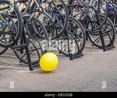 Palloncino giallo viene soffiato lungo il terreno di fronte a parcheggio biciclette Foto Stock