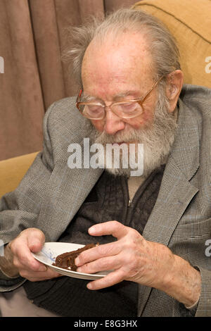 Il vecchio uomo di mangiare la torta di compleanno Foto Stock