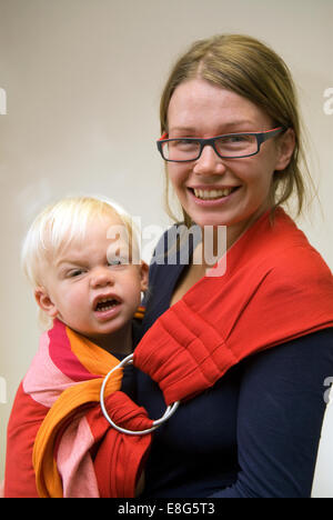 Giovane madre che porta il suo figlio di 2 anni in una fionda bambino, Farnham, Surrey, Regno Unito. Foto Stock