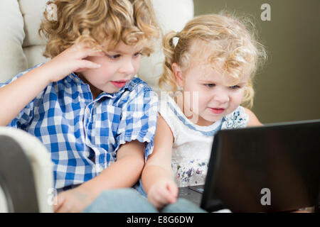 Adorabili giovane fratello e sorella e utilizzando il loro computer portatile insieme. Foto Stock