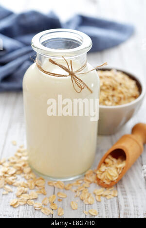 Oat latte in bottiglia bianca su sfondo di legno. Vegani e vegetariani concetto di latte. Foto Stock