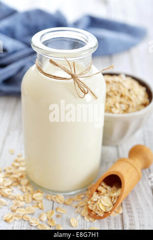 Oat latte in bottiglia bianca su sfondo di legno. Vegani e vegetariani concetto di latte. Foto Stock