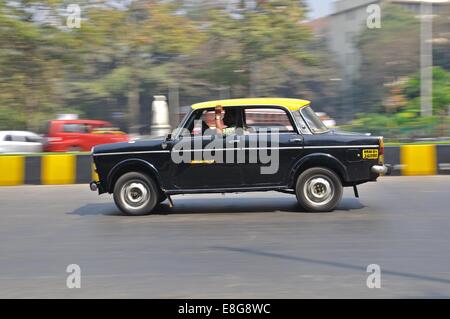 Un Hindustan Ambasciatore Taxi guidando lungo una strada di città di Mumbai, India Foto Stock