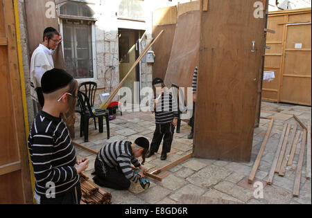 Gerusalemme. Il 7 ottobre, 2014. Ultra-Orthodox bambini ebrei aiutano a costruire un Sukkah, un rituale di booth utilizzati durante la festa ebraica di Sukkot a un quartiere Religioso di Gerusalemme il 7 ottobre, 2014. Attento ebrei costruire strutture temporanee per la settimana di festa per commemorare i 40 anni di viaggiare nel deserto dopo l'esodo dalla schiavitù in Egitto. Questo anno di Sukkot inizia giovedì. © Gil Cohen Magen/Xinhua/Alamy Live News Foto Stock