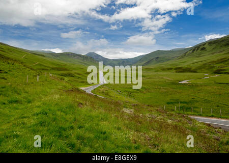 Spettacolare vasto paesaggio & strada stretta avvolgimento attraverso il verde delle colline e montagne di Cairngorms National Park, Scozia Foto Stock