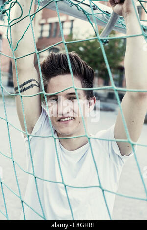 Ritratto di sorridere studente di scuola superiore dietro soccer net Foto Stock